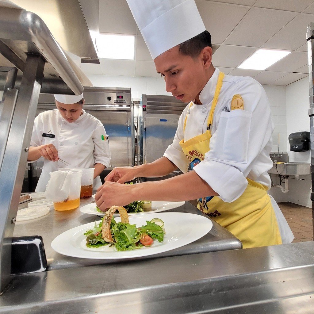 Culinary students training together, plating dishes in a professional kitchen