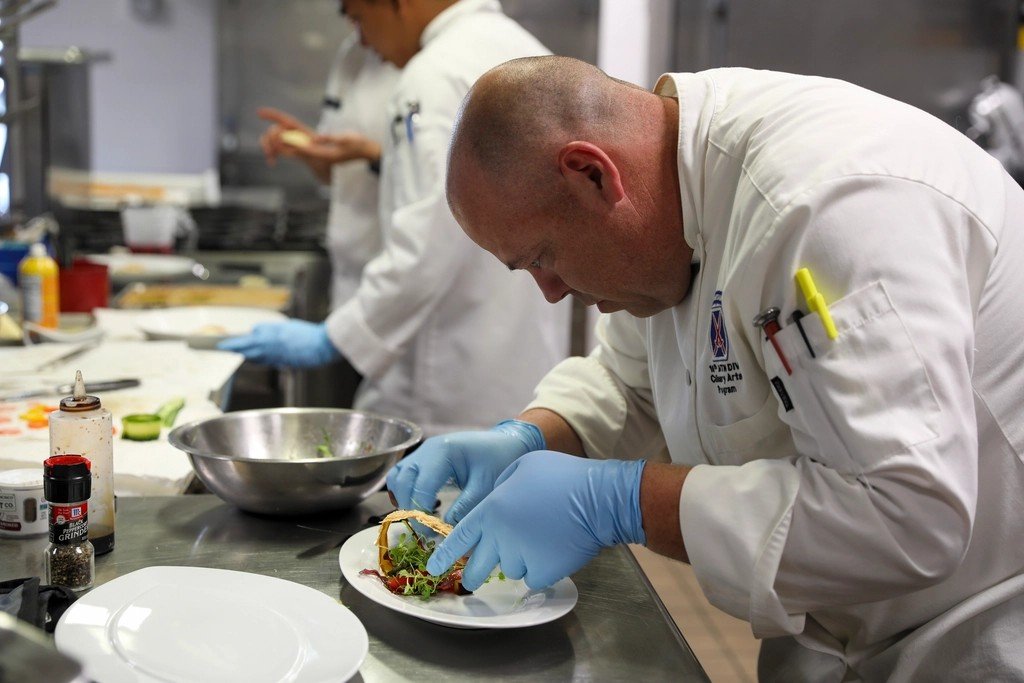Chef finishing a plated dish, a moment of completion
