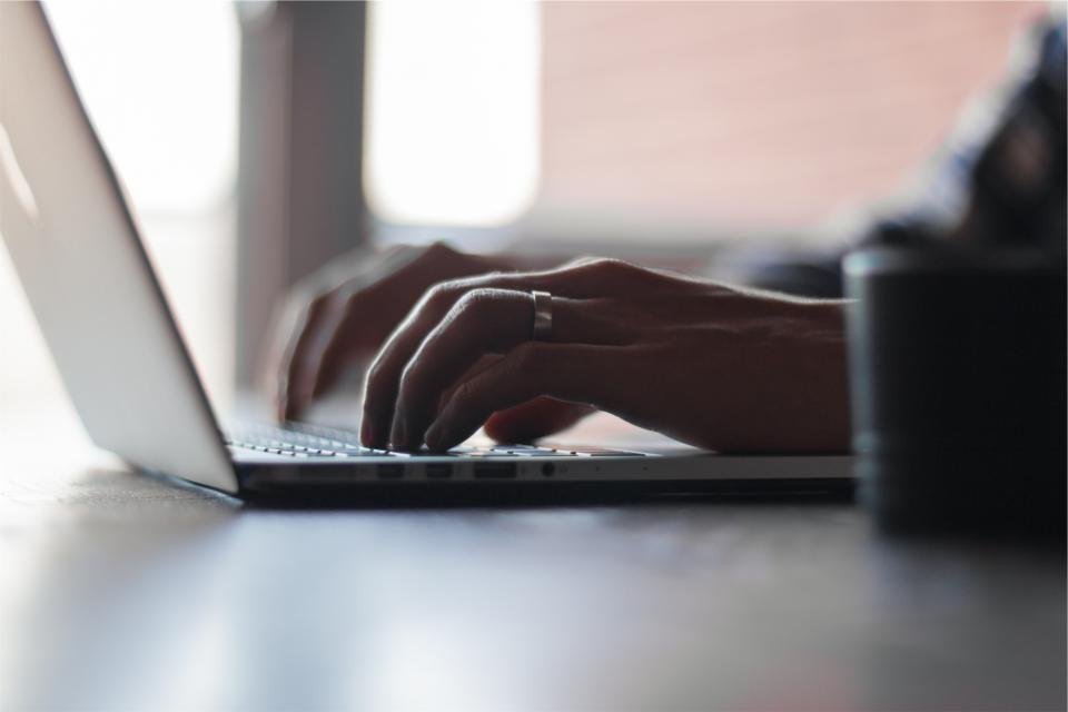 Hands typing on a laptop, checking a credential online